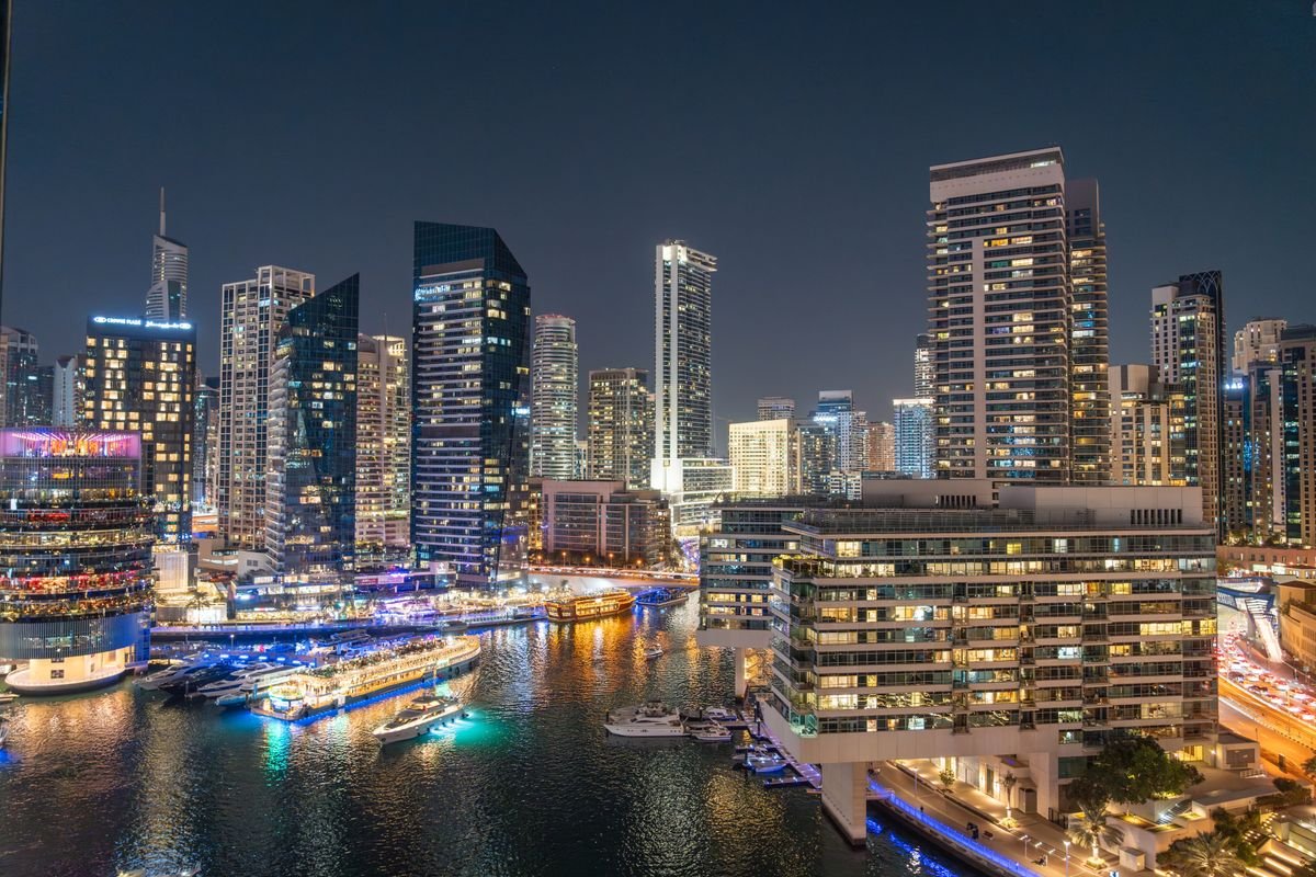Dubai Marina skyline lit up at night with illuminated skyscrapers and waterfront