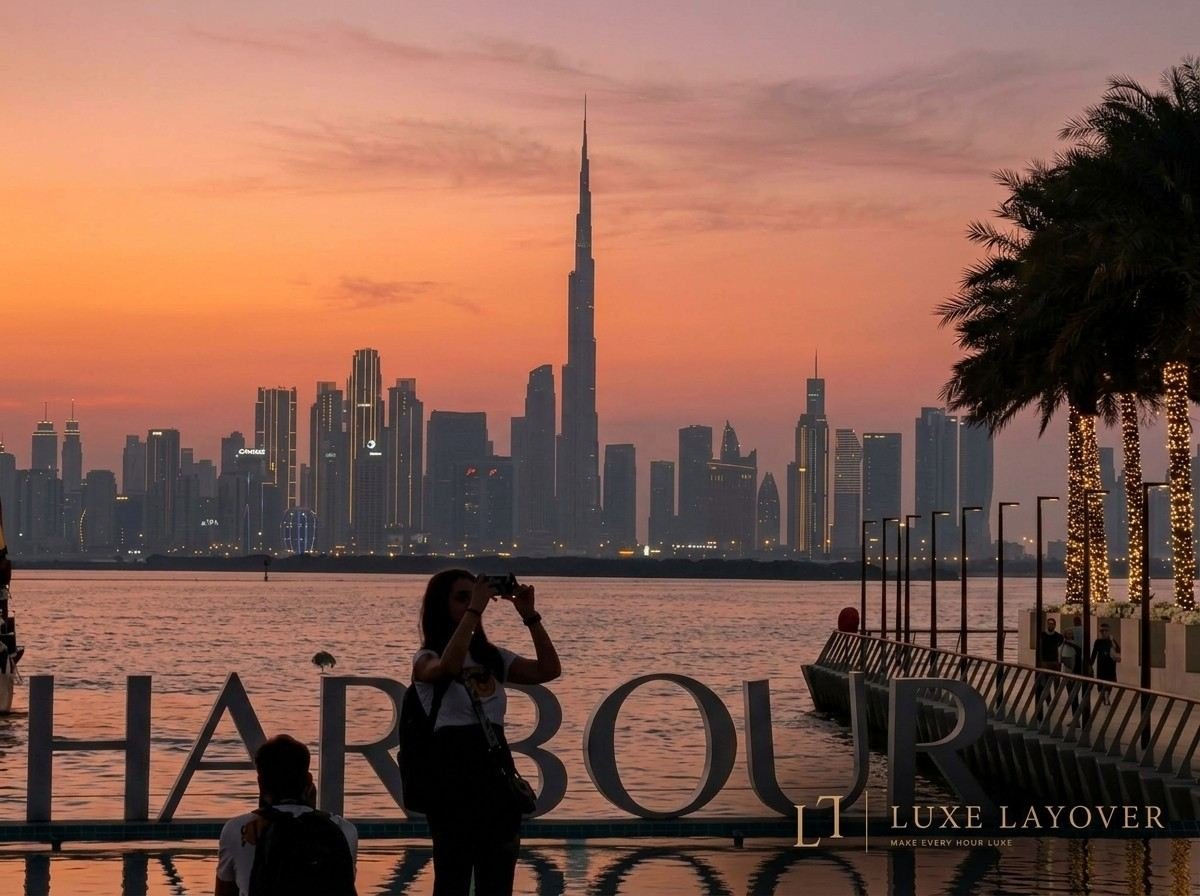 A couple standing at a railing silhouetted against a sunset over Dubai Harbour with the skyline