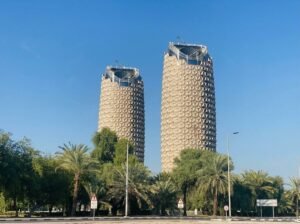 Two of the Etihad Towers skyscrapers viewed from a palm-lined street