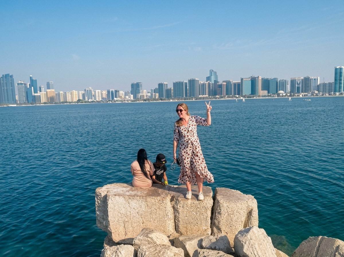 Two friends posing on waterfront rocks with the Abu Dhabi skyline behind them