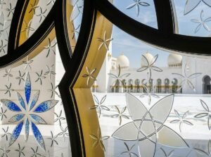 A close-up of an ornate stained-glass floral window pattern inside a mosque