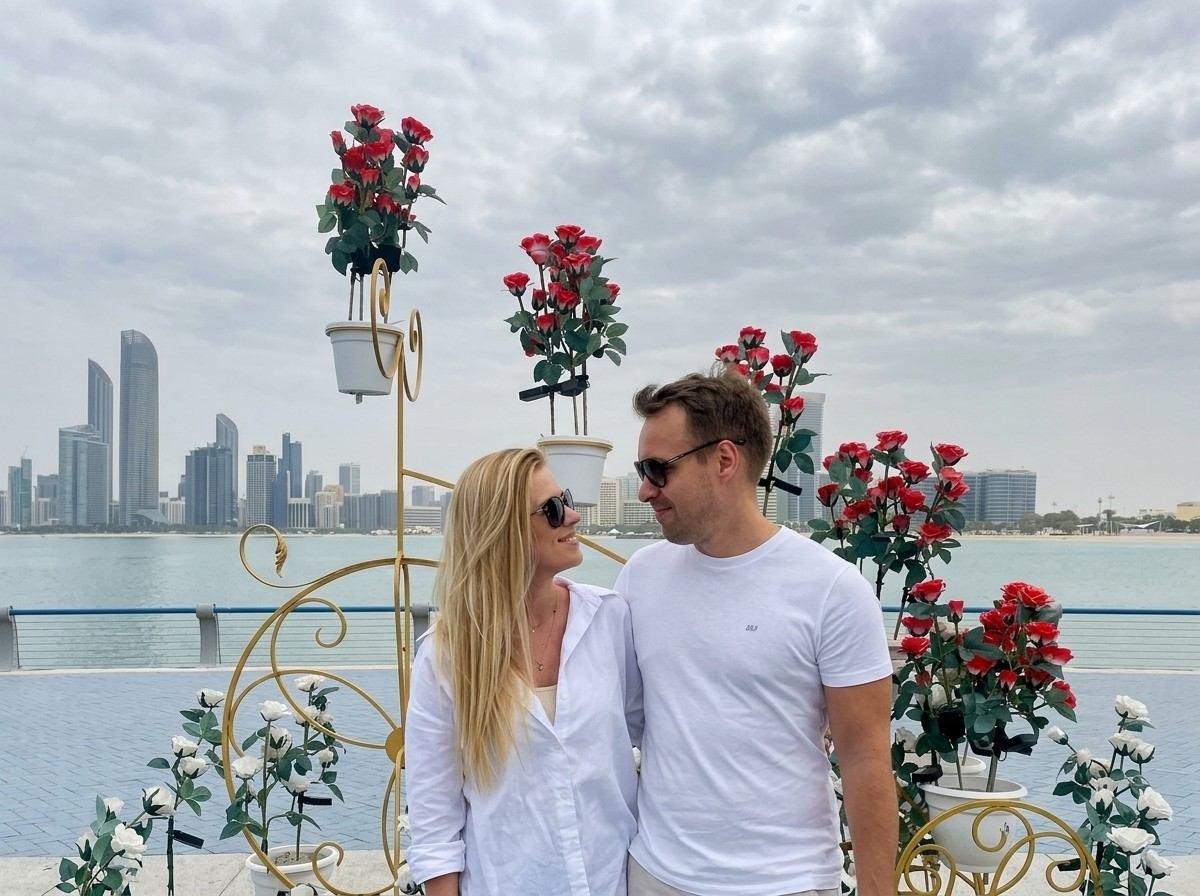 A couple posing together in a rose garden with the Abu Dhabi skyline behind them