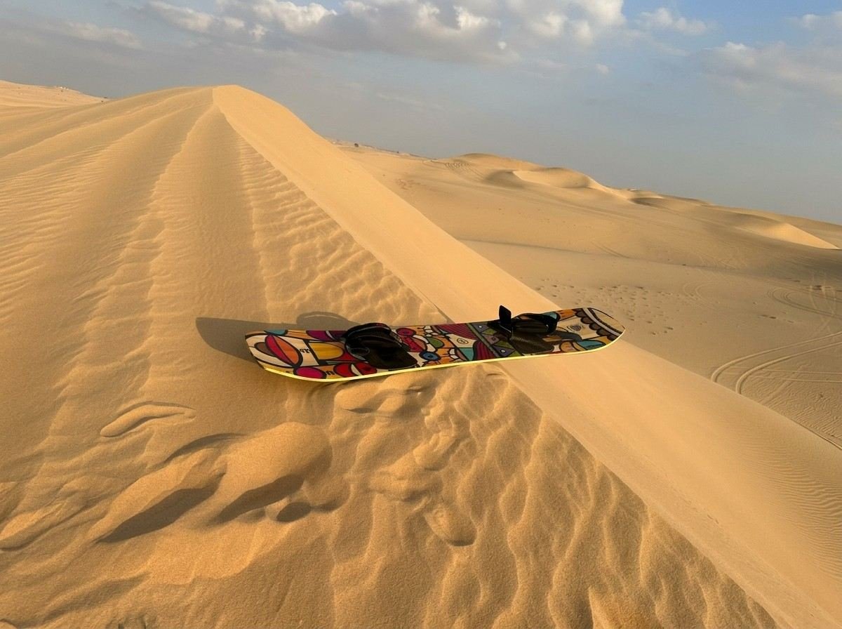 An aerial view of a dune buggy vehicle parked on a large sand dune